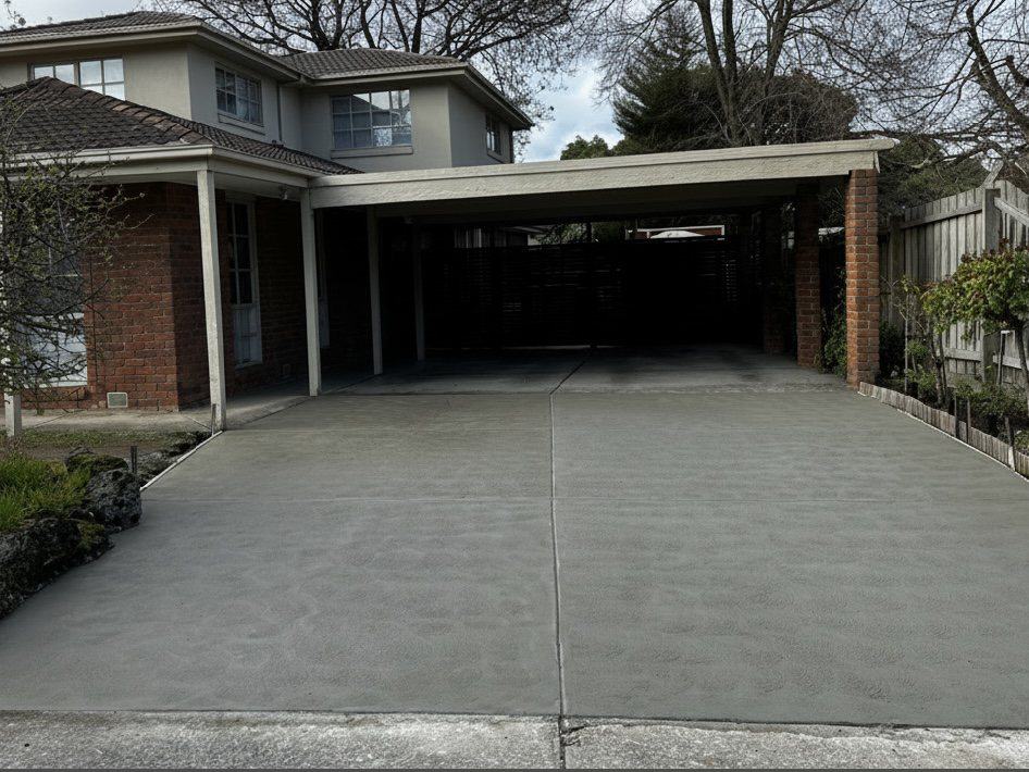 Replacement driveway running under the carport of an established brick home