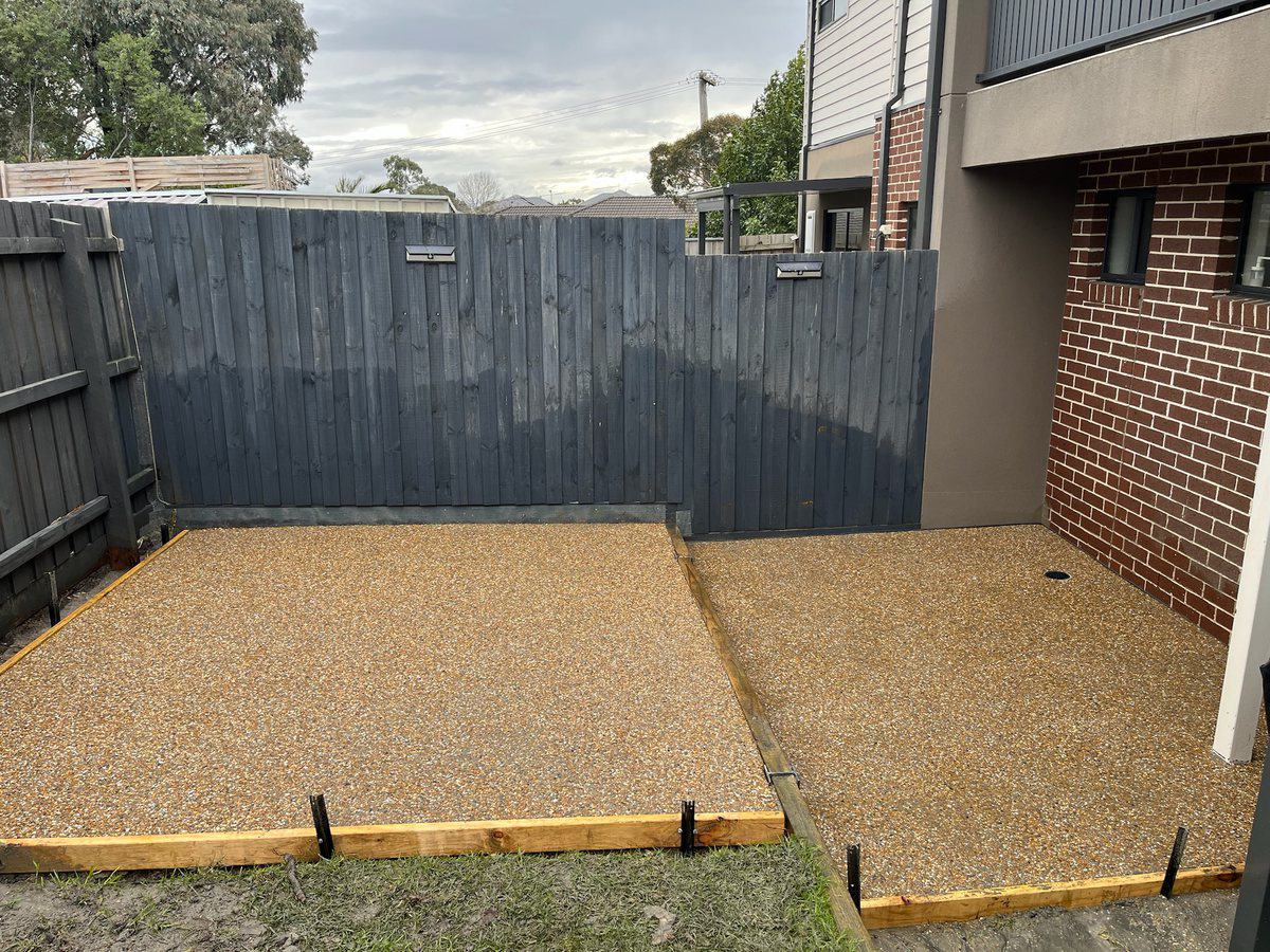 Gold exposed aggregate courtyard behind a townhouse, formwork still in place