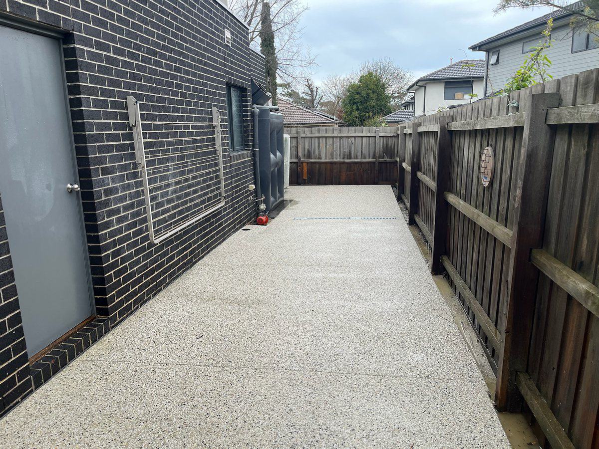 Exposed aggregate side path running between a house and the fence line